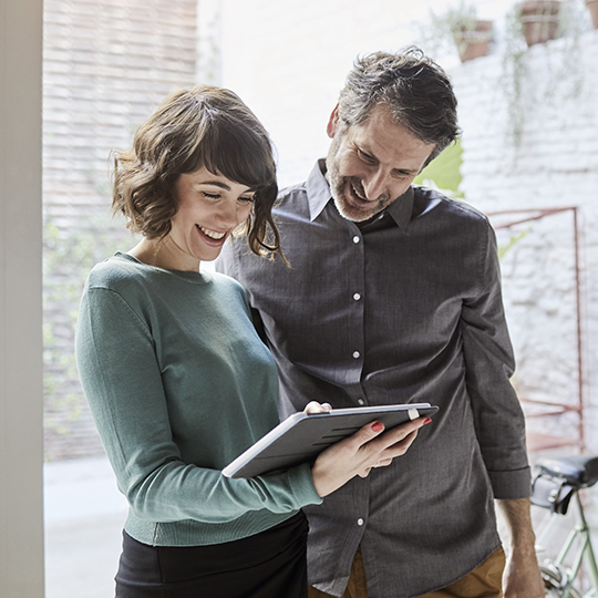 Eine Frau und ein Mann schauen auf ein Tablet