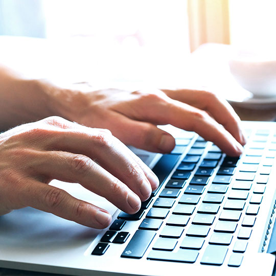 Close up of hands typing on a laptop