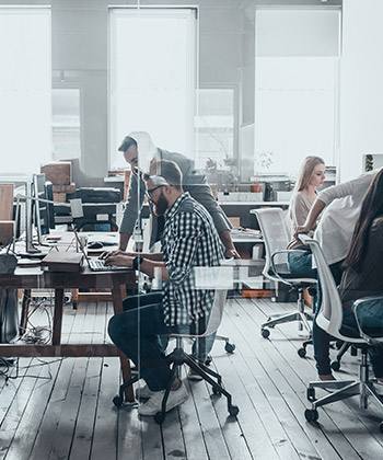 Bescheidene Anfänge employees working in a glass office